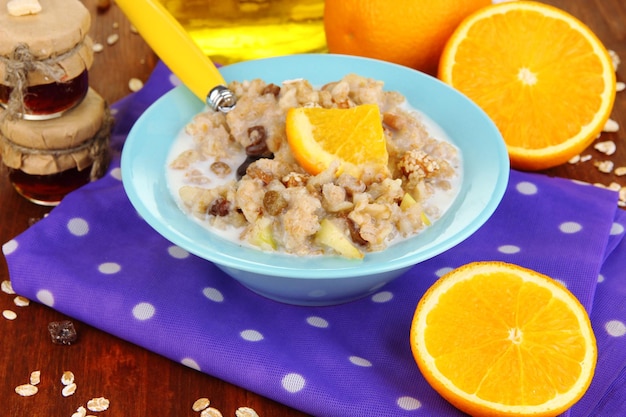 Useful oatmeal in bowl with fruit on wooden table closeup