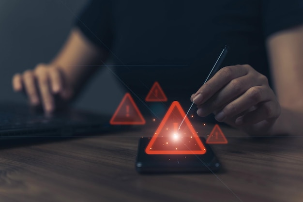Photo user is using mobile phone with triangle caution warning sign for notification error and maintenance concept hacker attacks and hacking data cyber crime cyber security