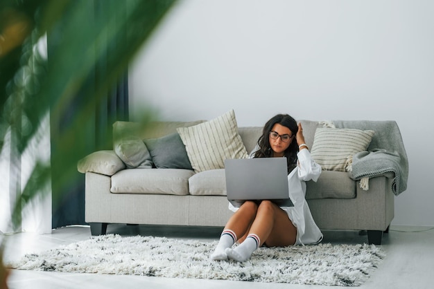 Uses laptop Woman in casual clothes is indoors at home