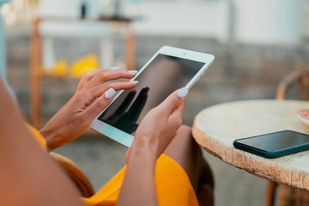 Uses a new gadget in a summer cafe watching the news a woman
holds a tablet in her hands