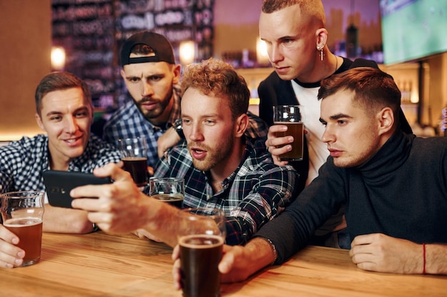 Uses phone Group of people together indoors in the pub have fun at weekend time