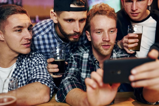 Uses phone Group of people together indoors in the pub have fun at weekend time