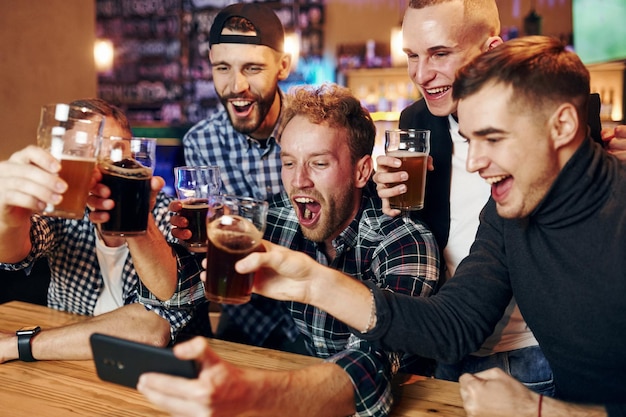 Uses phone Group of people together indoors in the pub have fun at weekend time