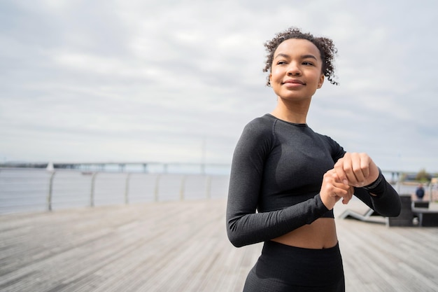 スポーツ用のスマートウォッチと腕のトラッカーを使用している女性ランナーがフィットネス ランニングをしている