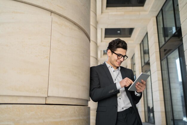 Uses a tablet writes a message to a client a man in glasses and a formal suit a businessman