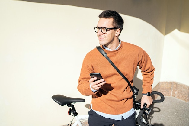 職場に行く男性サイクリストの 10 代のフリーランサーが携帯電話でアプリを使用する