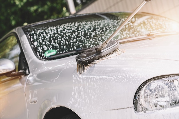 Using a brush to wash a car at a car wash station