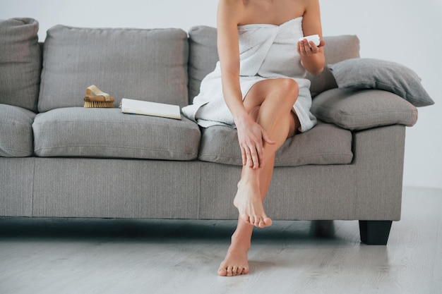 クリームを使って足の皮膚をきれいにする 若い女性が家にいる 美しさの概念