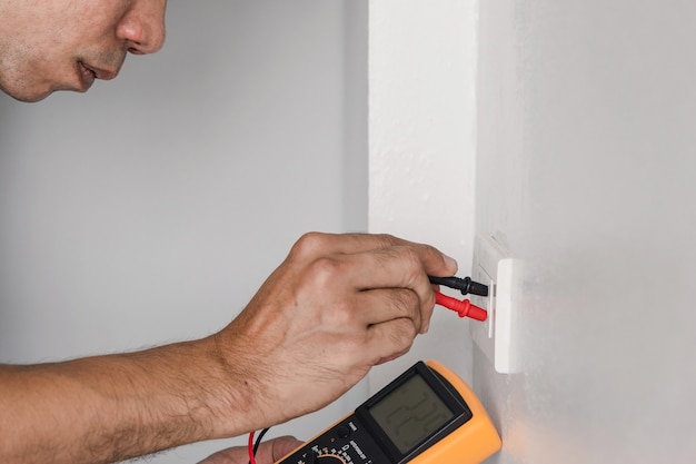 using a digital meter to measure the voltage at the power outlet in on the wall.