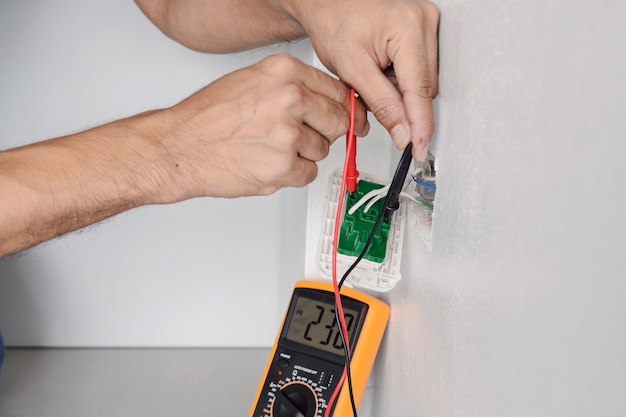 using a digital meter to measure the voltage at the power outlet in on the wall.