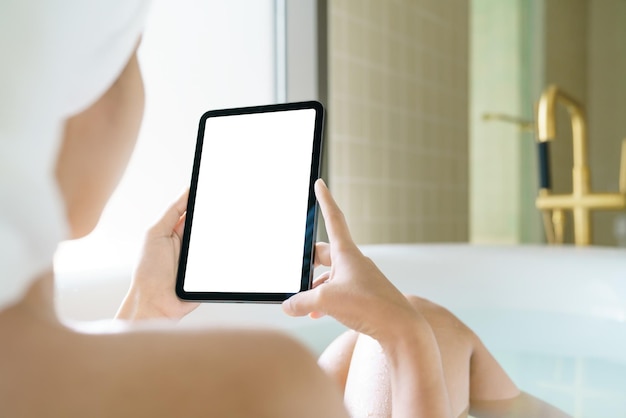 Utilizzo della tavoletta digitale donne che tengono la tavoletta digitale mentre si immergono nella vasca da bagno in moring