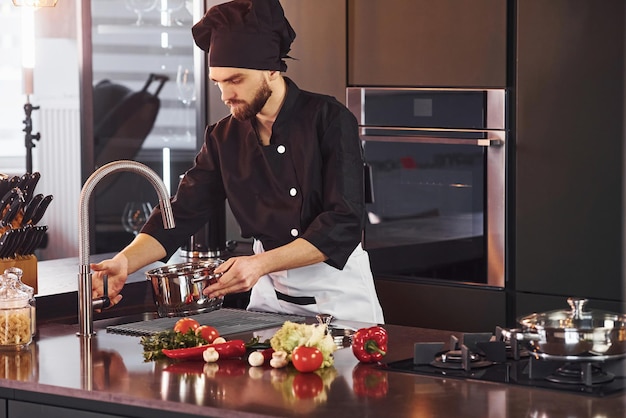 Using equipment Professional young chef cook in uniform working on the kitchen with vegetables