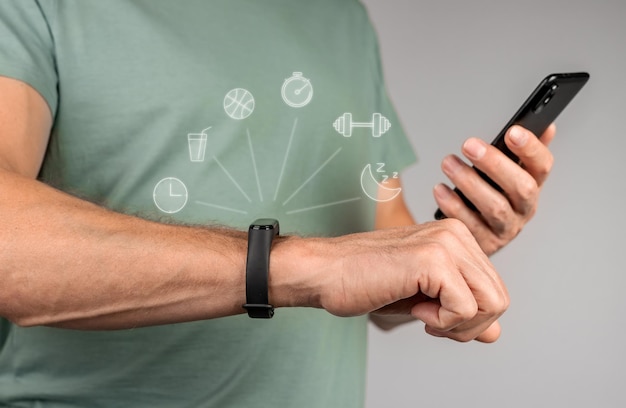 Photo using fitbit fitness bracelet and mobile phone hands with sport smartwatch and holding smartphone for sync