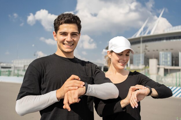 Using a fitness bracelet a man and a woman doing an active\
workout running in the city