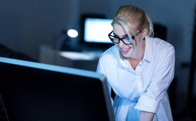 Using future technologies. Smiling positive attractive secretary standing in the office and using smart gadgets while expressing interest