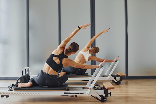 Использование тренажерного зала Две женщины в спортивной одежде и со стройными телами вместе проводят день фитнес-йоги в помещении