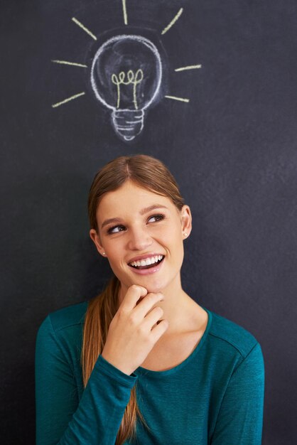 Photo using illustrations to teach her students cropped shot of an attractive young woman standing in front of a blackboard