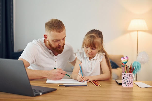 Usare il laptop il padre con la sua piccola figlia è a casa insieme