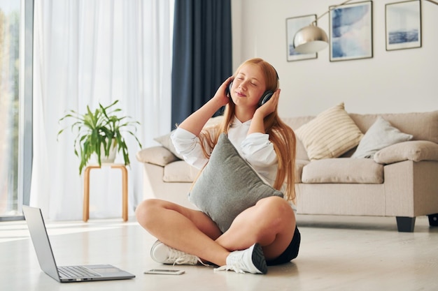 Using laptop Female teenager with blonde hair is at home at daytime