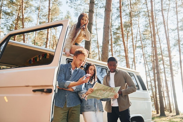 Using map group of young people is traveling together in the\
forest at daytime