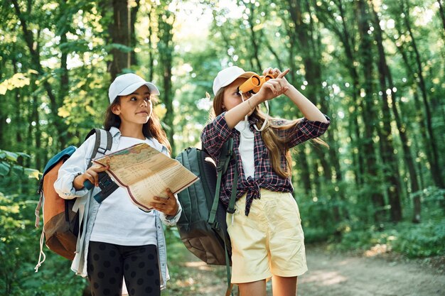 Photo using the map two girls is in the forest having a leisure activity discovering new places