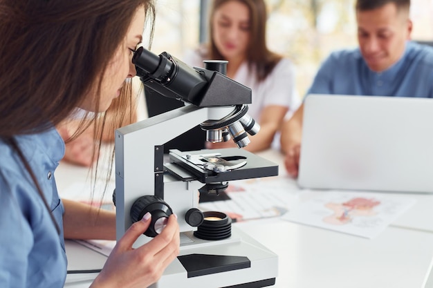 Using microscope Group of young doctors is working together in the modern office