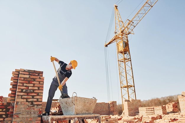 Utilizzo di showel operaio edile in uniforme e equipaggiamento di sicurezza ha un lavoro sulla costruzione