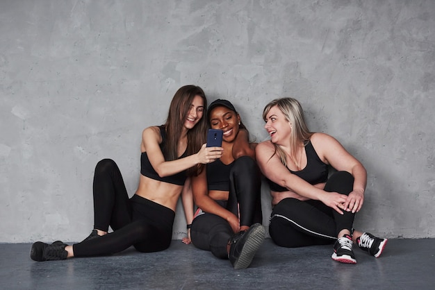 Using smarphone. Group of multi ethnic women sitting