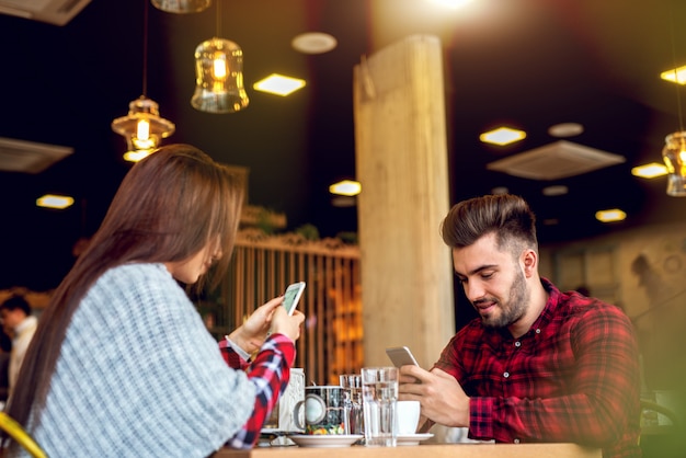 Using smart phones at cafe bar.