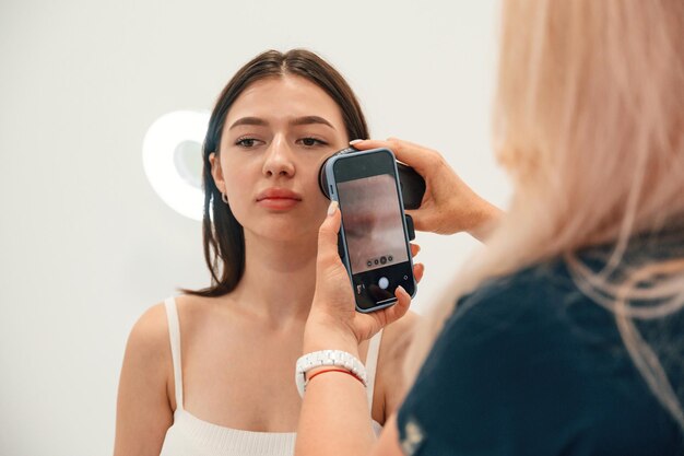 Foto utilizzare lo smartphone ottenere una foto della procedura di ringiovanimento in una clinica di cosmetologia donne in un salone di bellezza