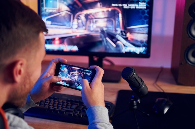 Using the smartphone Online streamer playing FPS shooter game at home