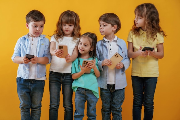 using smartphones kids are together against yellow background
