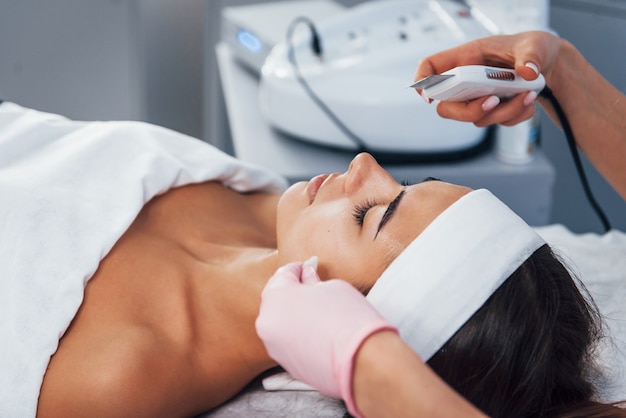 Using special device. Close up view of woman that lying down in spa salon and have face cleaning procedure.