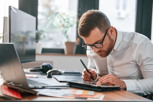 Foto l'uso del tablet l'uomo in abiti formali lavora in un ufficio moderno