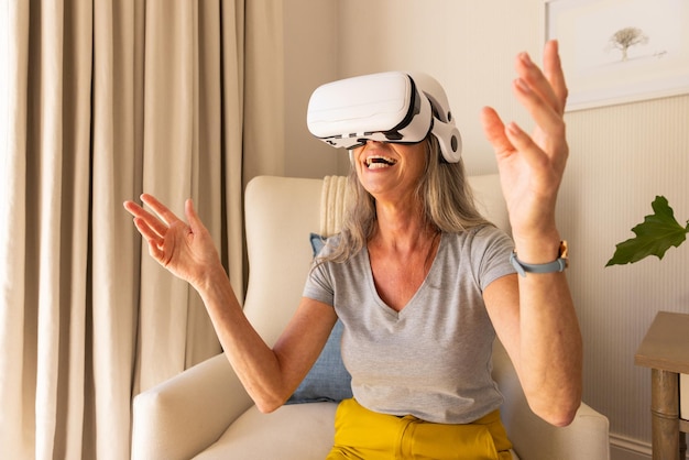 Используя VR наушники зрелая женщина наслаждается опытом виртуальной реальности дома