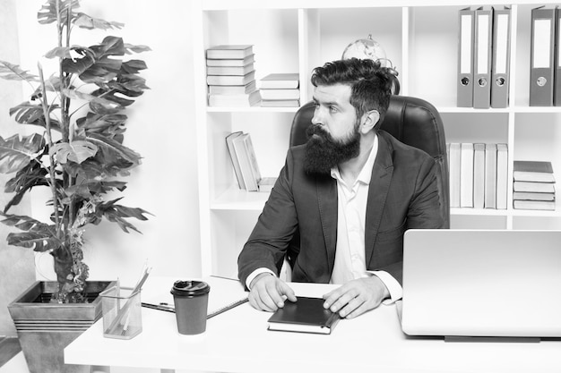 Usual day in office Man bearded hipster boss sit in leather armchair office interior Boss at workplace Manager formal clothing corporate style working Business people concept Busy boss in office