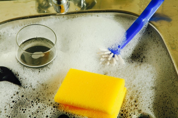 Foto utensiliën bedekt met zeep in de keuken wastafel