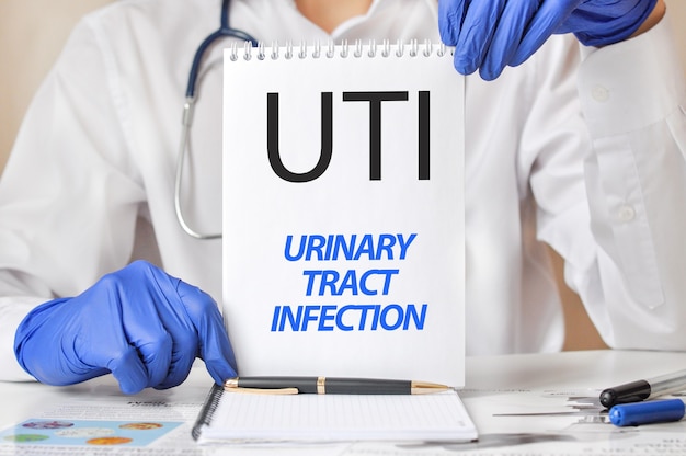 의사의 손에 UTI 카드. 텍스트 UTI- 요로 감염, 의료 개념에 대 한 짧은 종이 한 장을 들고 파란색 장갑에 의사의 손.
