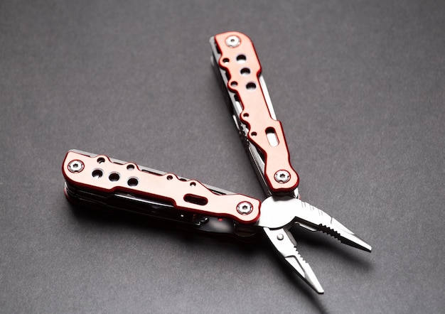 Utility tool knife with pliers and nozzles on a gray background