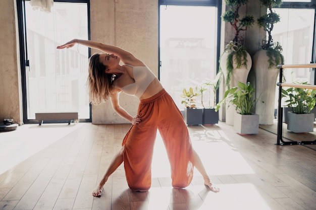 Utthita exercise on a mat on the floor surrounded by indoor plants in a fitness studio asana pose