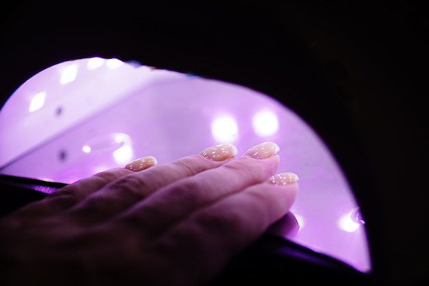 Photo uv lamp gel polish manicure process in a beauty salon