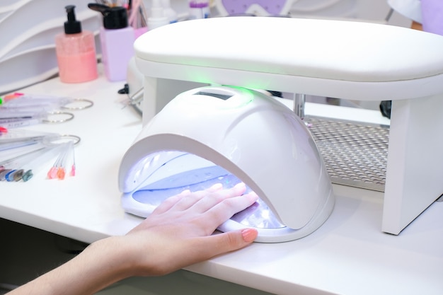 UV lamp gel polish manicure process. Salon procedure. The master coats the clients nails with a shellac