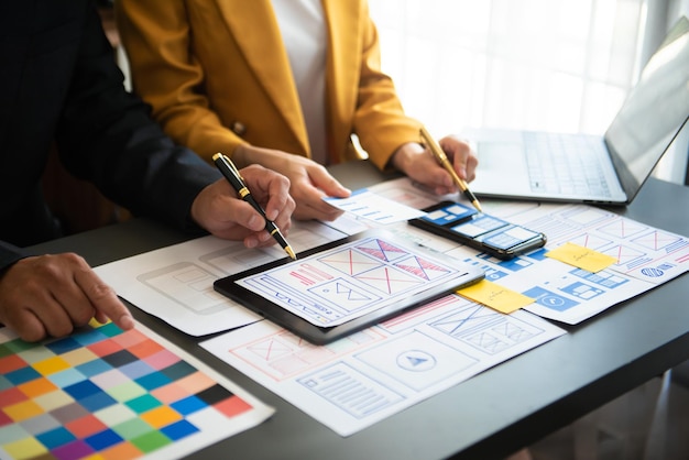 UX developer and ui designer brainstorming about mobile app interface wireframe design with customer breif and color code at officexA