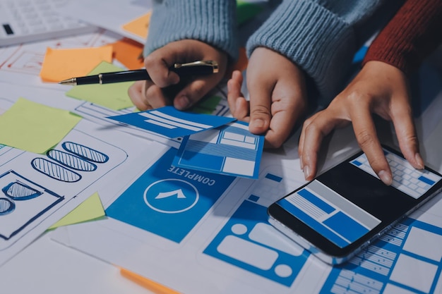 UX UI designer testing prototype on a phone discussing and brainstorming on wireframes for a website and mobile app prototype in the concept of website and mobile application design concept