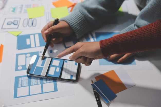 UX UI designer testing prototype on a phone discussing and brainstorming on wireframes for a website and mobile app prototype in the concept of website and mobile application design concept