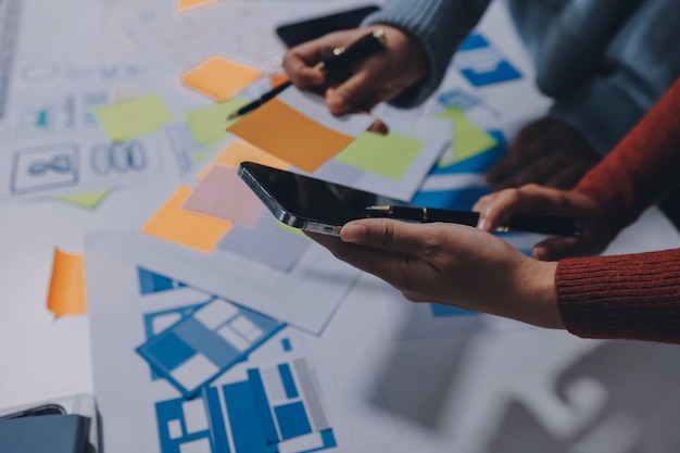 UX UI designer testing prototype on a phone discussing and brainstorming on wireframes for a website and mobile app prototype in the concept of website and mobile application design concept