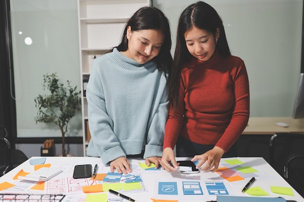 ux ui designer testing prototype on a phone discussing and brainstorming on wireframes for a website and mobile app prototype in the concept of website and mobile application design concept