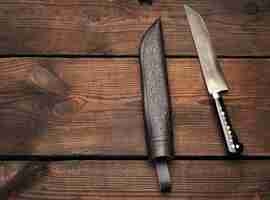 Photo uyghur uzbek traditional universal sharp knife with a black handle on a brown wooden backgrou