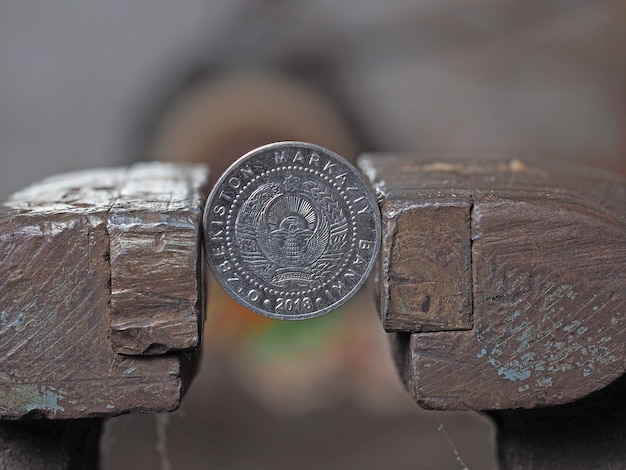 Uzbek coin som clamped in a metal vise