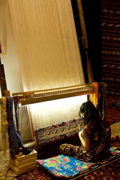 Uzbek girl weaving carpet in carpet workshop, bukhara,\
uzbekistan